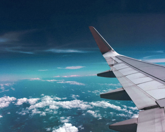 ala de avión en vuelo sobre nubes esponjosas contra un cielo azul oscuro.