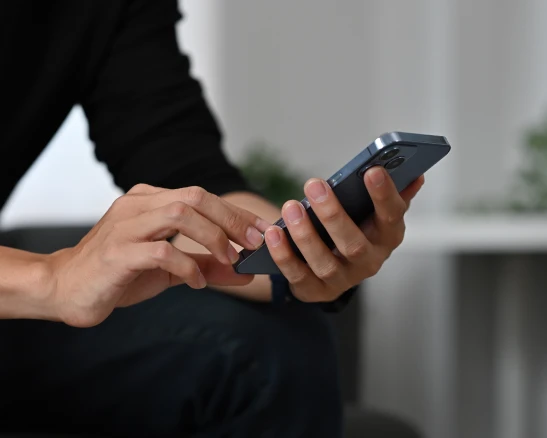 manos de una persona sosteniendo y tocando la pantalla de un teléfono inteligente