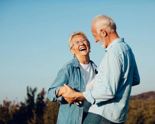 mujer y hombre mayor de la mano sonriendo en la naturaleza